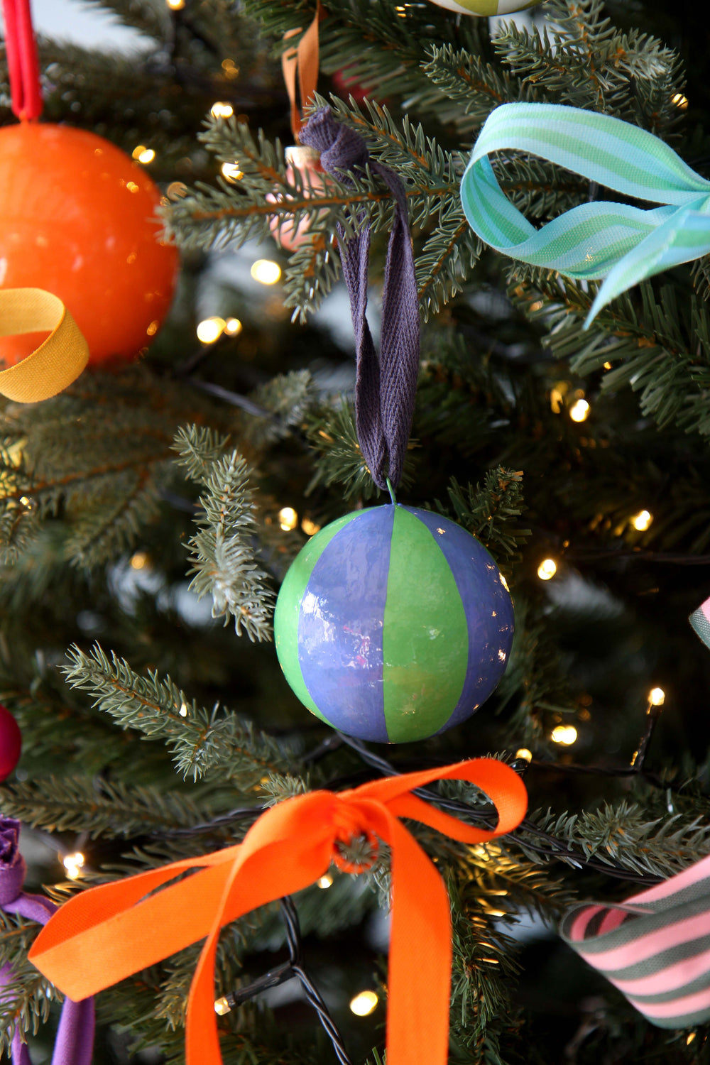 Decorative Christmas ornament with orange, purple, and green colors on a tree.