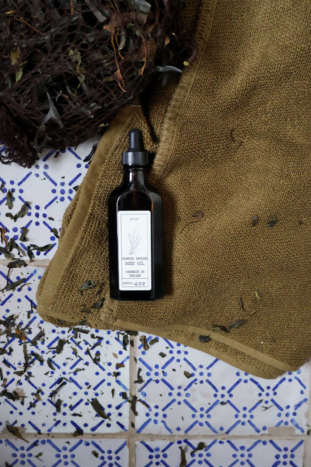 Black dropper bottle on a textured surface with a patterned tile background