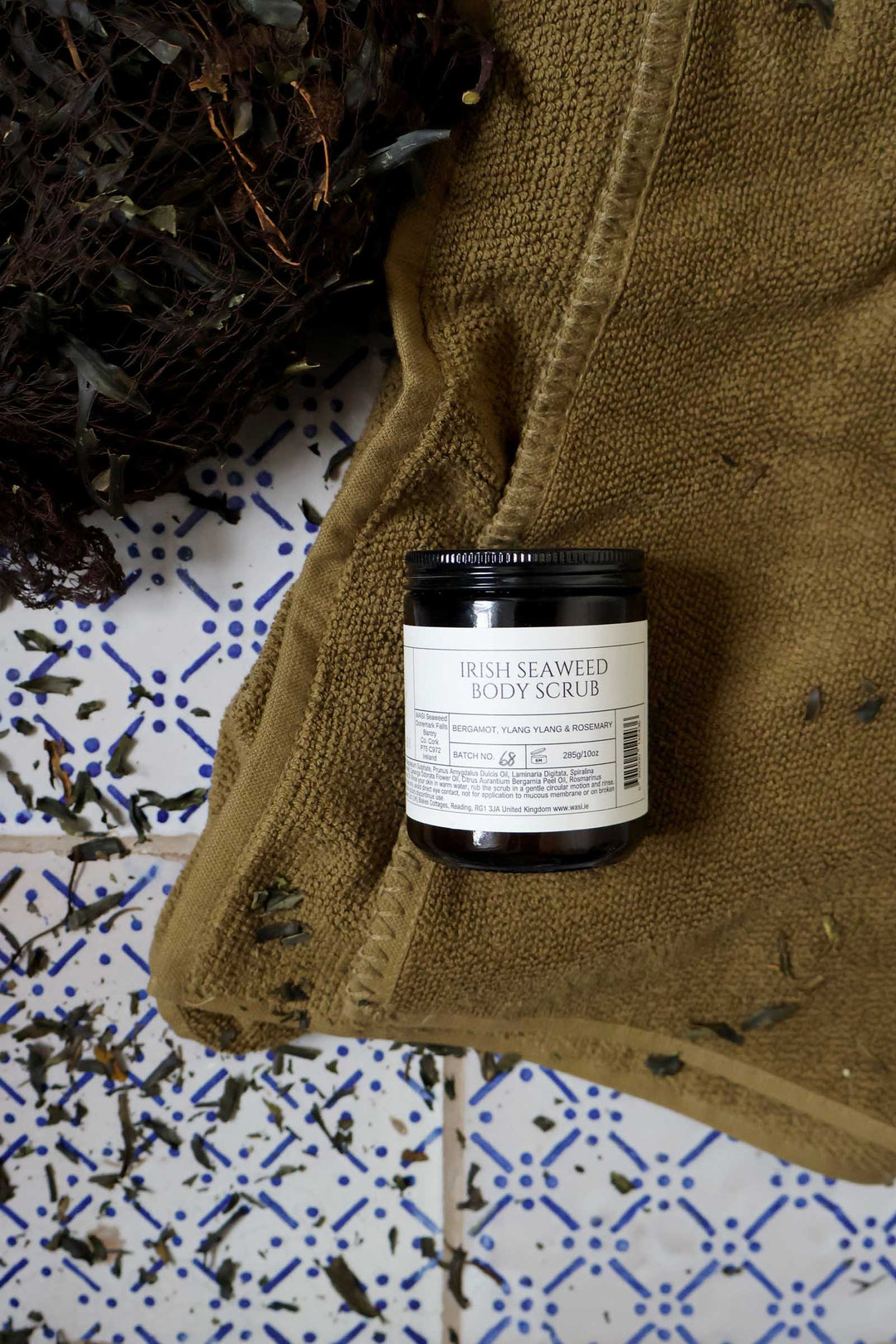 Jar of Irish Seaweed Body Scrub on a towel with a patterned tile background