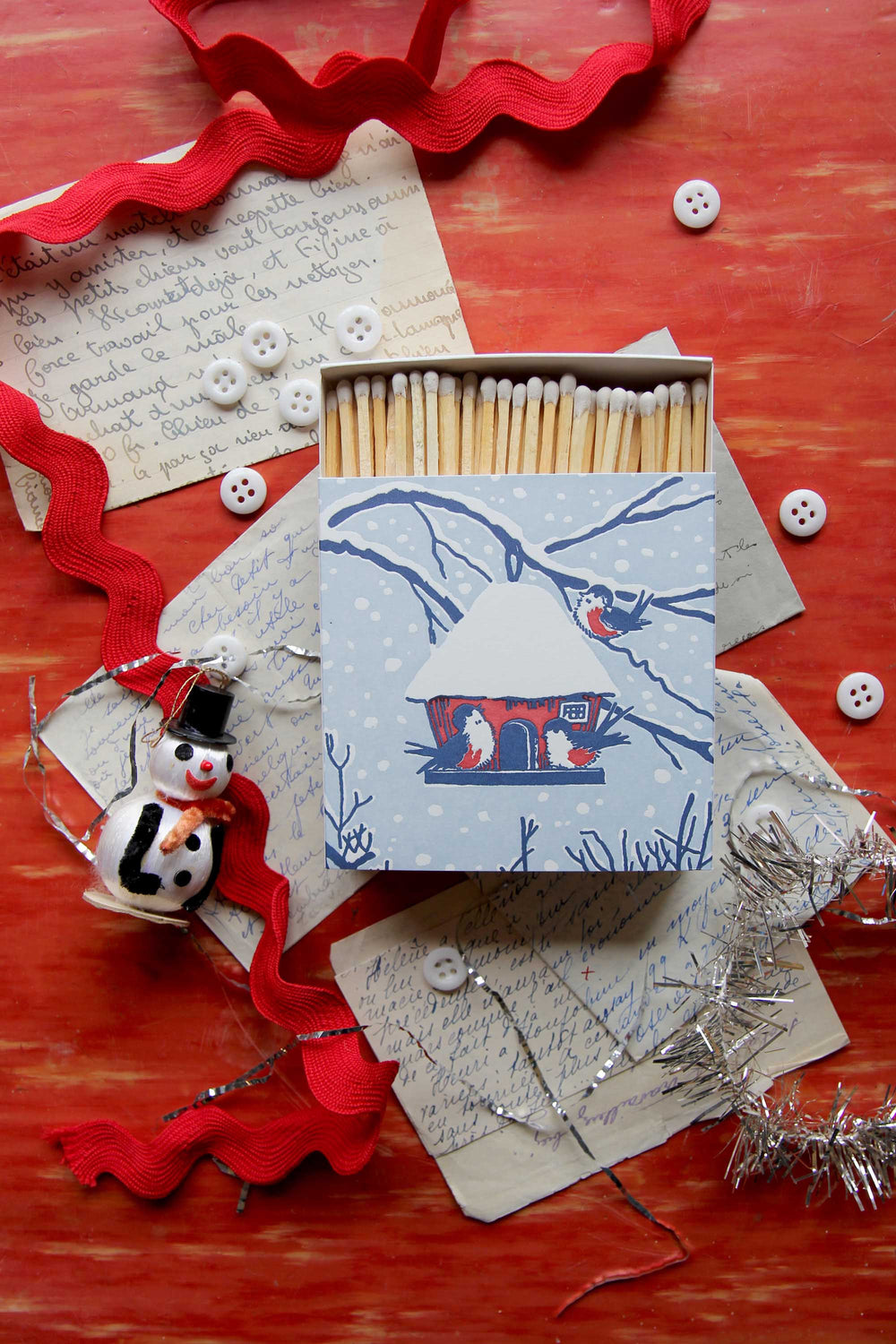 Matches with decorative box on a red surface with festive decorations