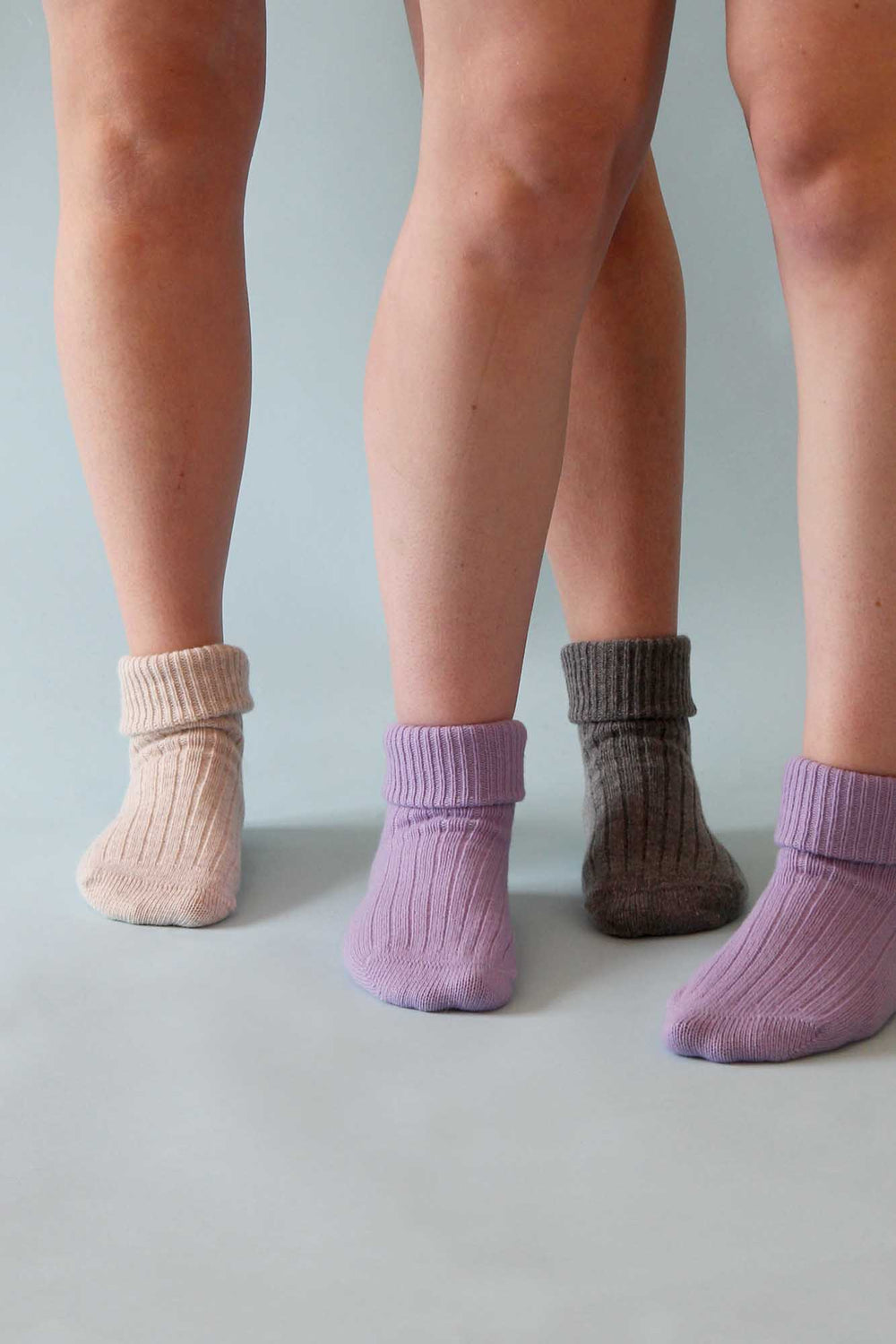 Three pairs of socks worn by different people on a neutral background