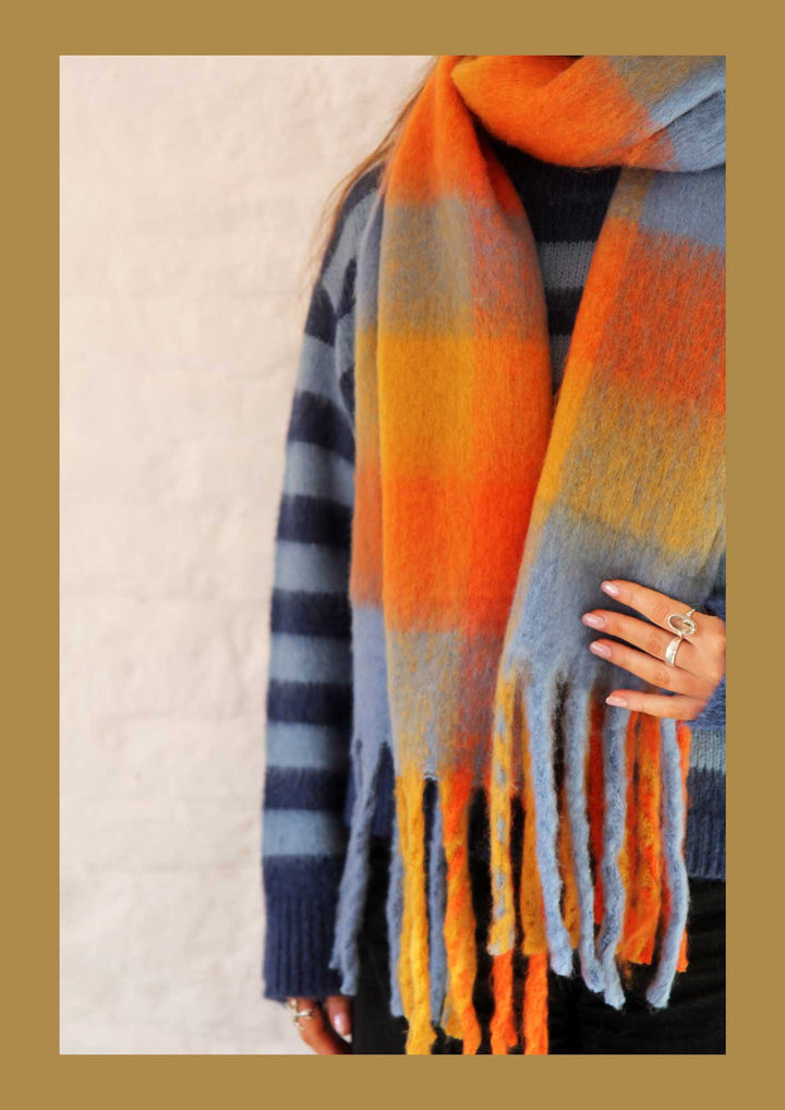 Plaid scarf with orange, blue, and gray colors on a neutral background