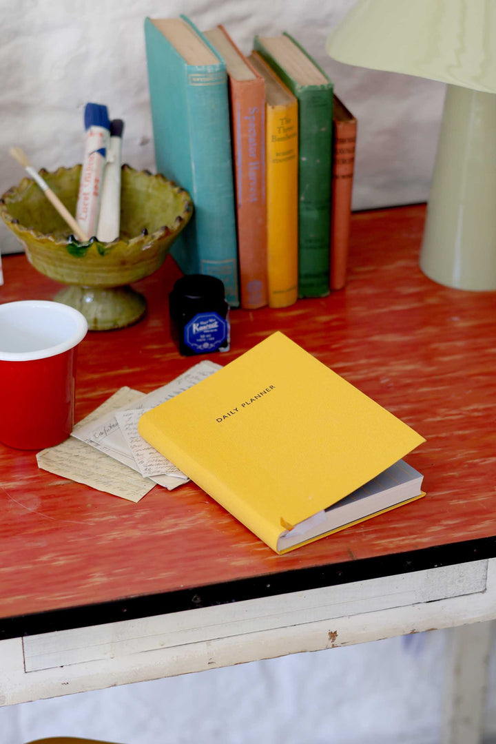 Yellow notebook on a red table with books and stationery items in the background