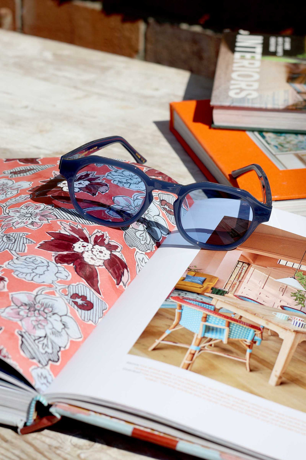 Blue sunglasses on an open book with a magazine in the background