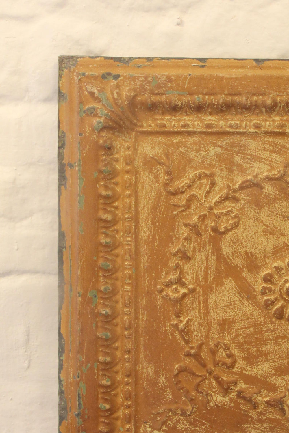 Close-up of an ornate gold frame with intricate designs on a textured beige background