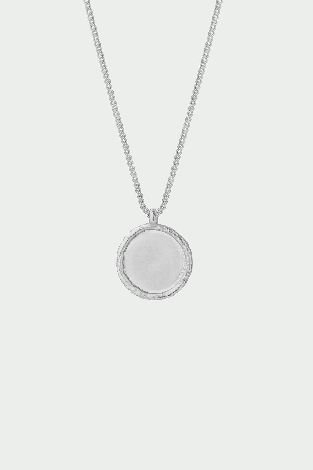 Silver necklace with a round pendant on a light gray background