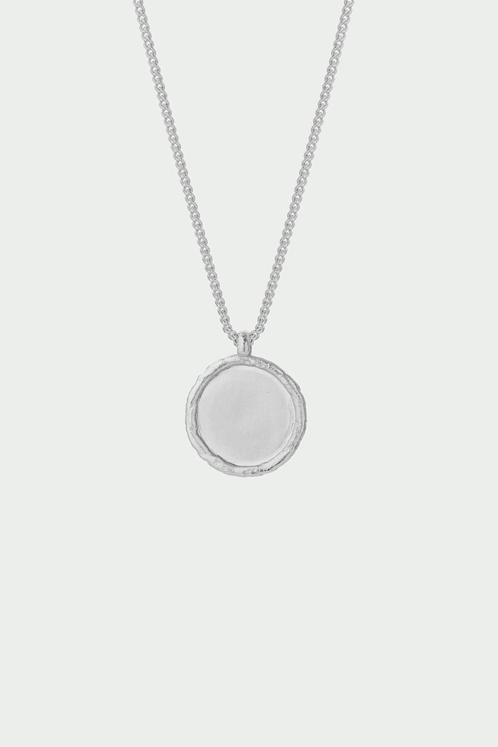 Silver necklace with a round pendant on a light gray background
