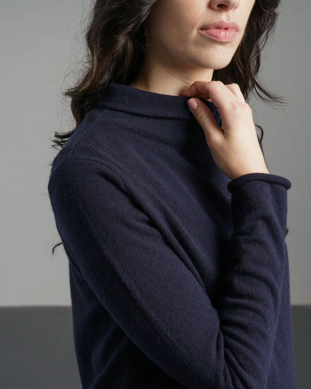 Person wearing a navy blue sweater against a gray background
