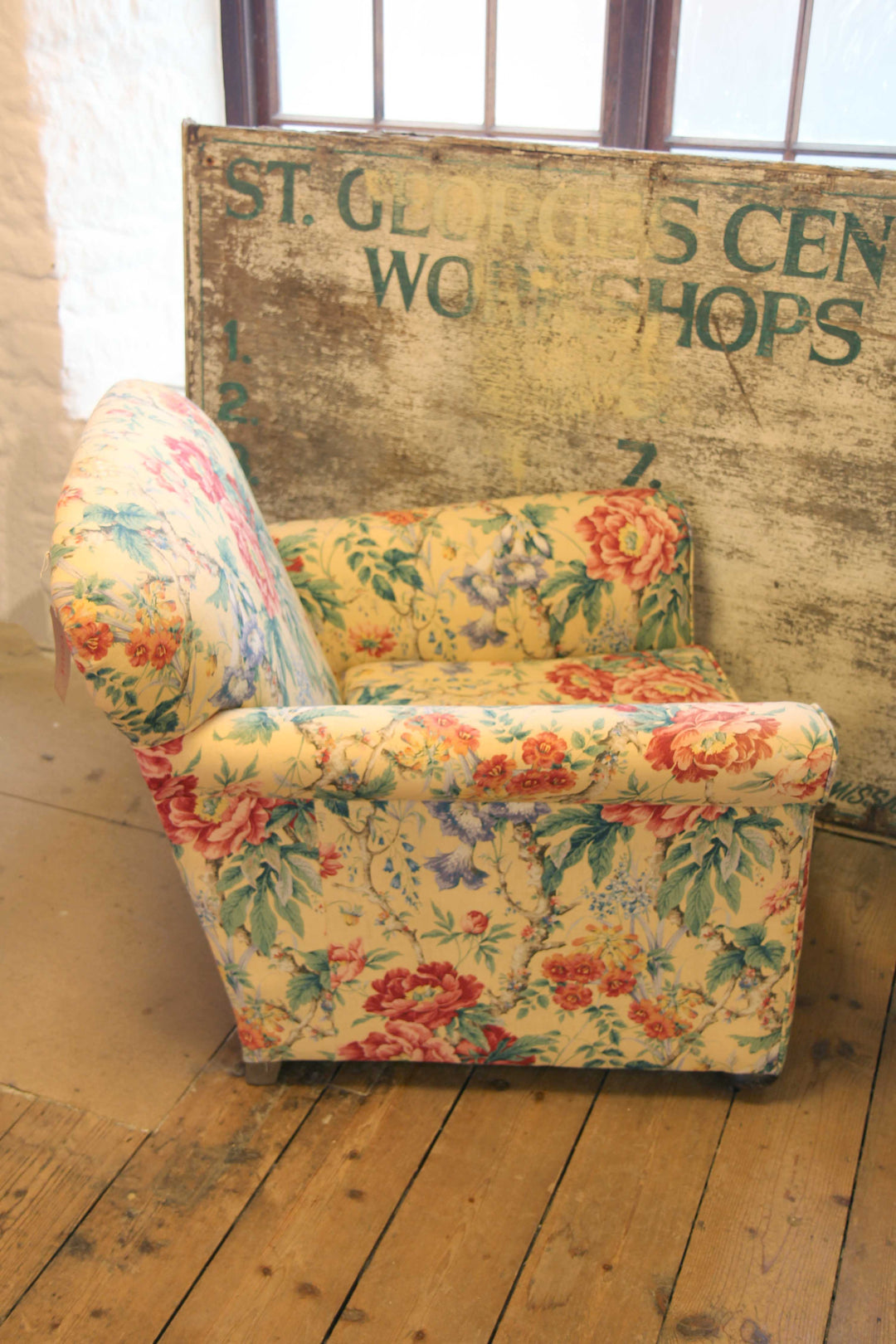 side view of yellow, red and green floral upholstered vintage armchair in domestic science shop