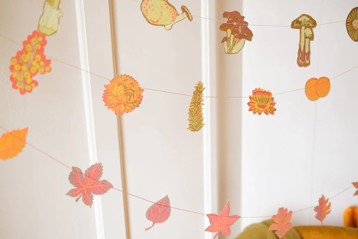 Decorative string with autumn-themed paper cutouts on a white curtain background