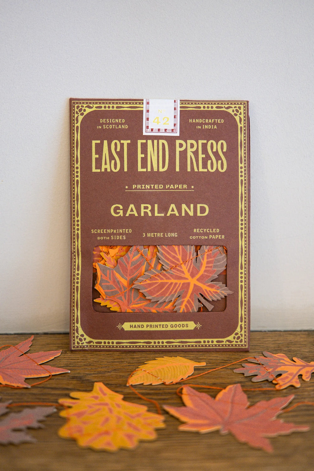 Packaging of East End Press Garland printed paper with decorative leaves on a wooden surface.