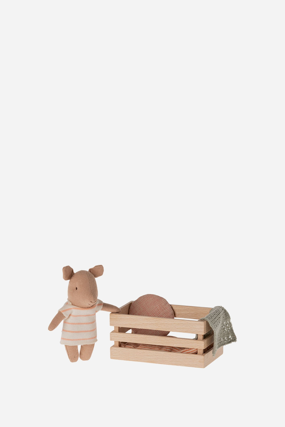 Small toy pig with a striped dress and a wooden crate with a pillow inside on a white background