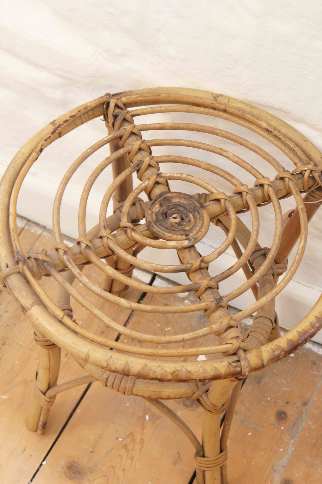 Wicker chair on a wooden floor with a white wall background