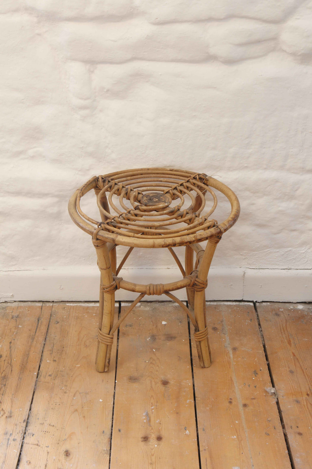 Wicker stool on a wooden floor with a textured white wall background