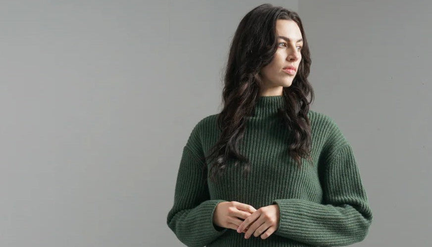 Woman wearing a green Bibico sweater against a plain background