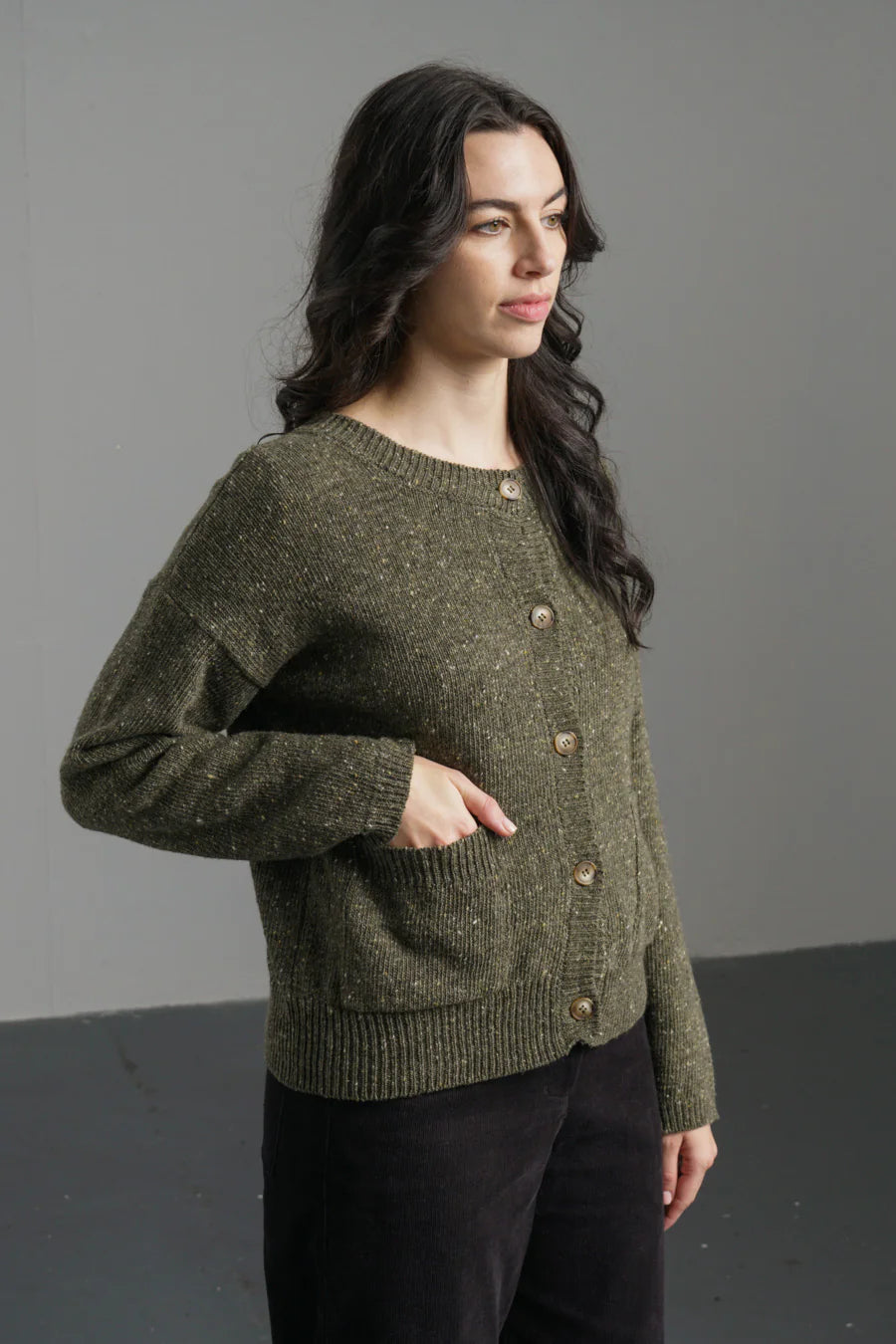 Woman wearing a green knitted sweater against a gray background