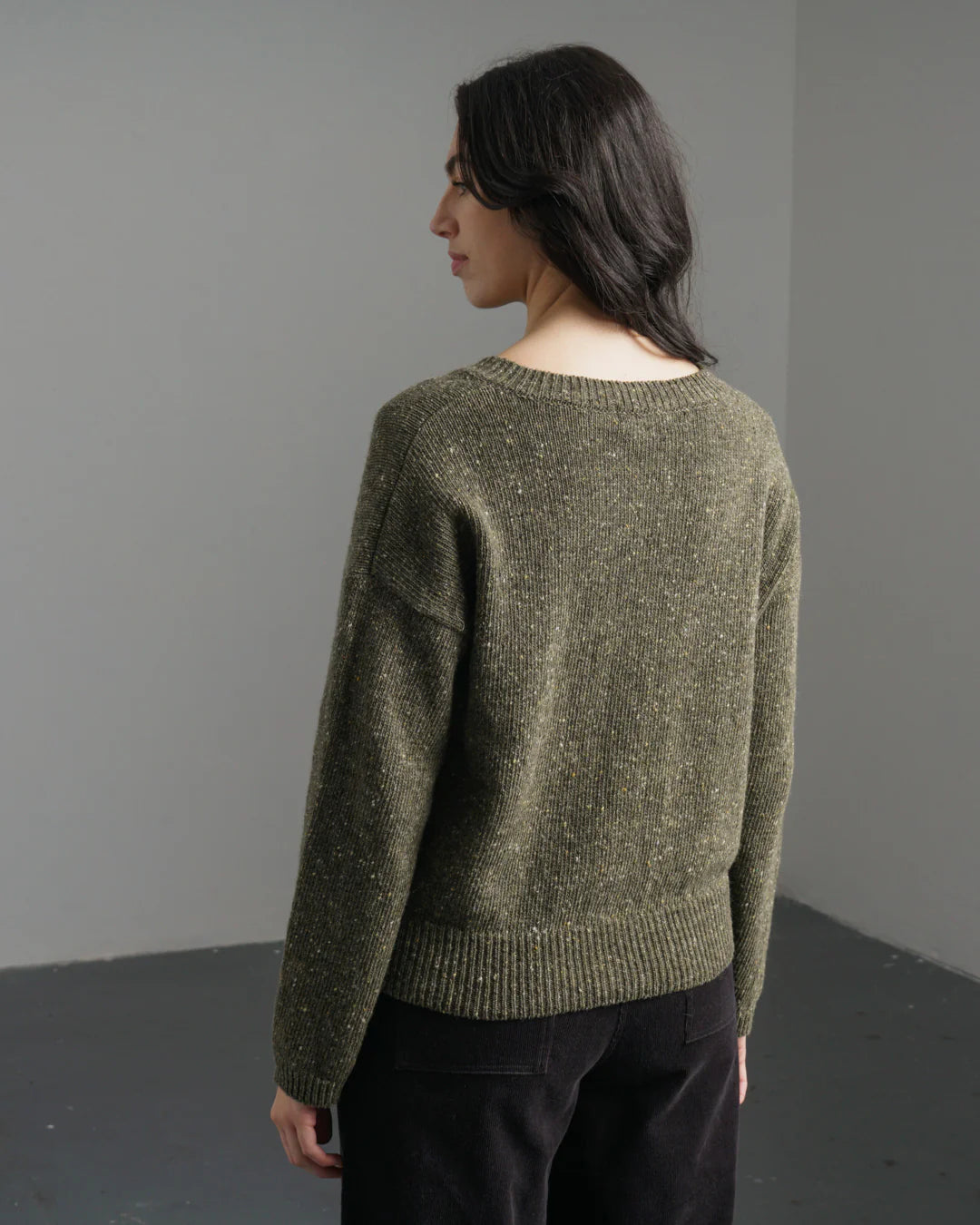 Person wearing a green sweater against a plain background