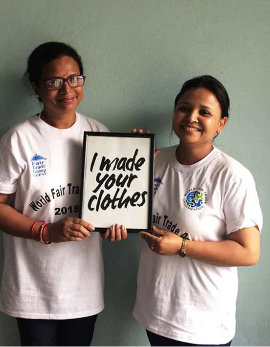 Two people wearing World Fair Trade shirts holding a sign.