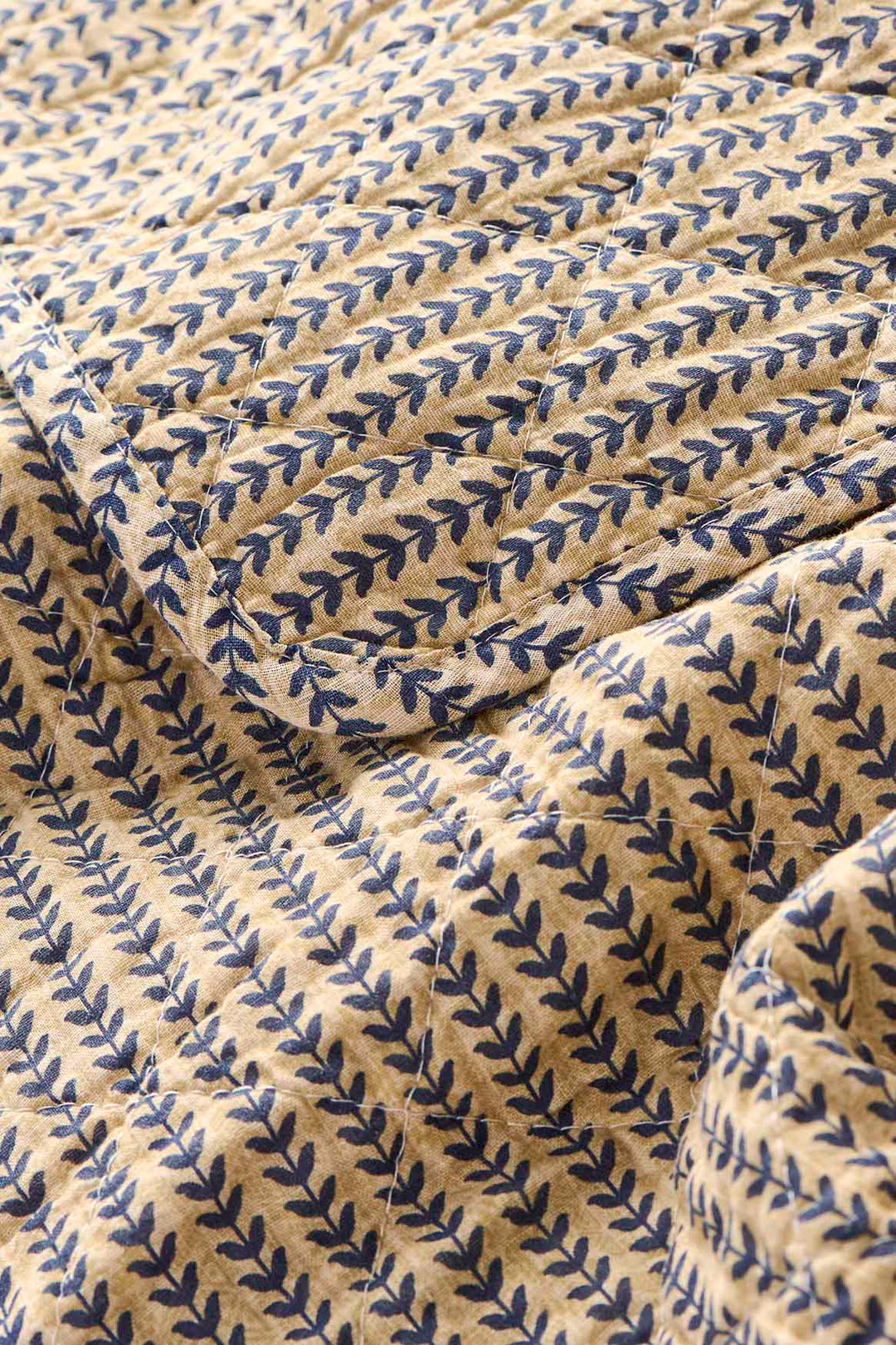 Textured fabric with blue leaf pattern on beige background