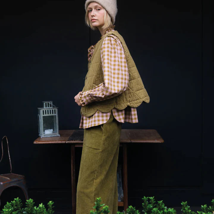 Person wearing a green outfit with a checkered shirt in a dark setting