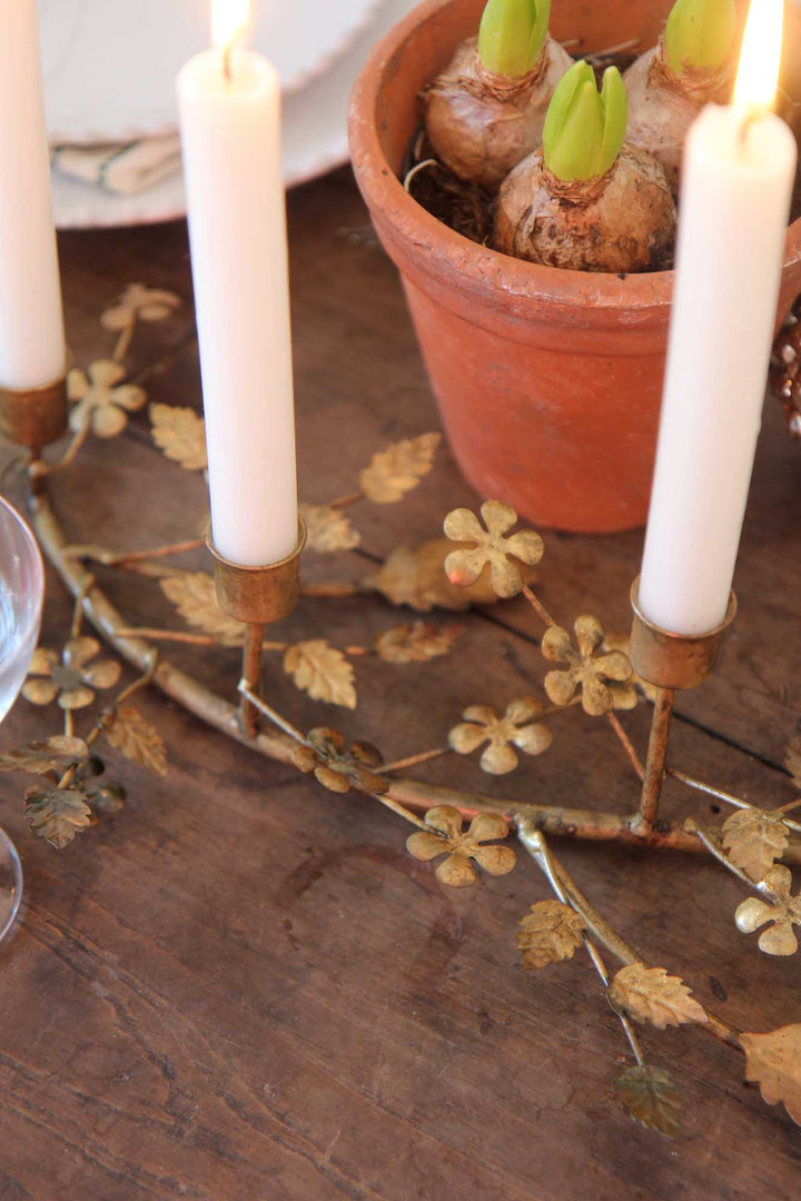 Decorative candle holder with candles and a potted plant on a wooden surface