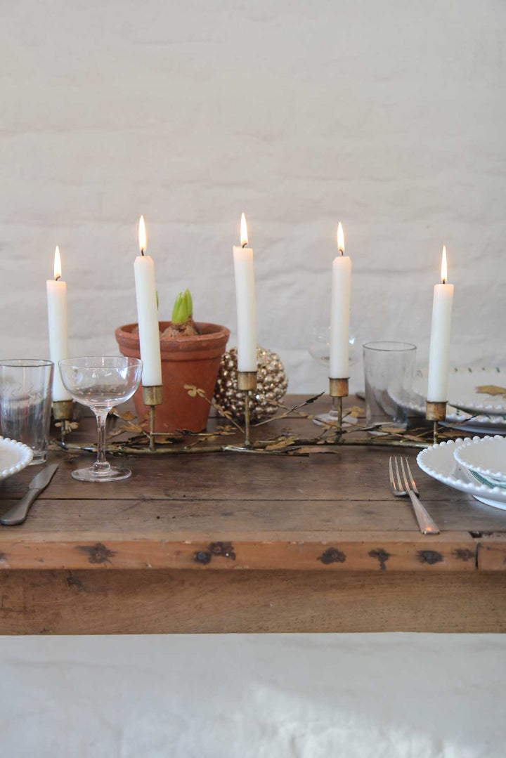 Dining table setup with candles, glasses, and decorative items on a wooden surface.
