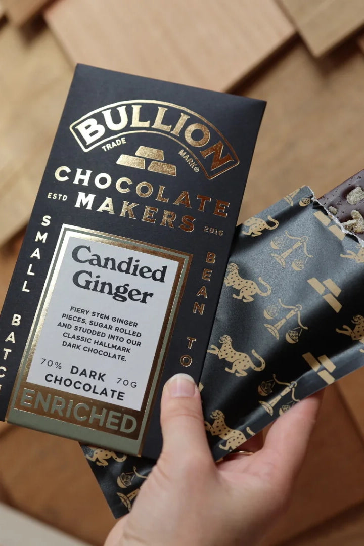 Bullion Chocolate Makers Candied Ginger chocolate bar held by a hand on a wooden surface