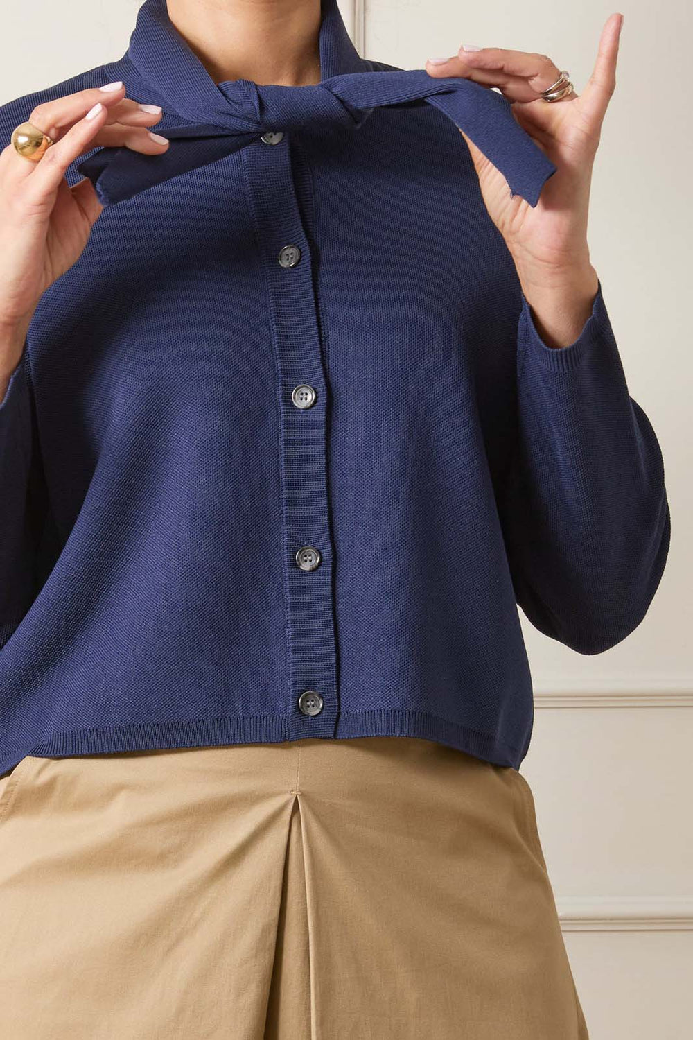 Navy blue cardigan with a bow detail worn by a person, against a neutral background.