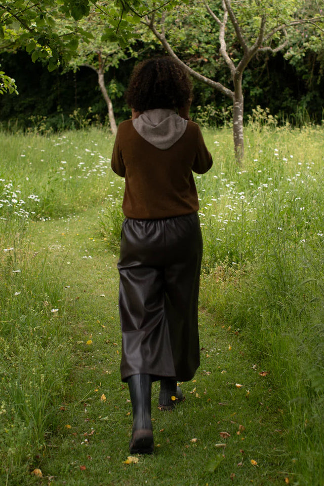 Person walking through a grassy field with trees and flowers