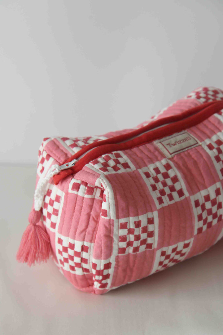 Pink checkered pouch with tassel on a light gray background