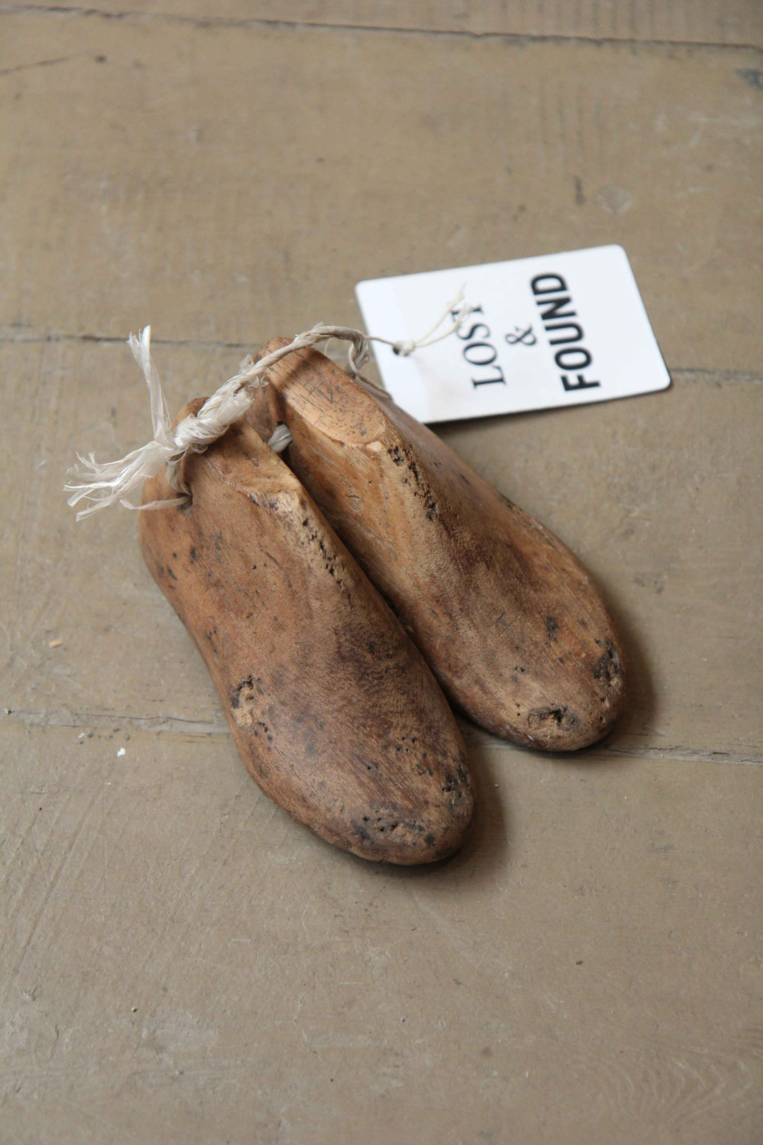Pair of wooden shoes lasts with a 'Lost & Found' tag on a wooden floor
