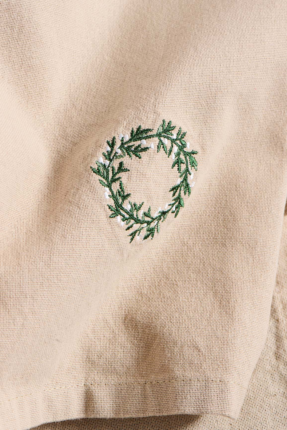 Beige fabric with a green embroidered wreath design