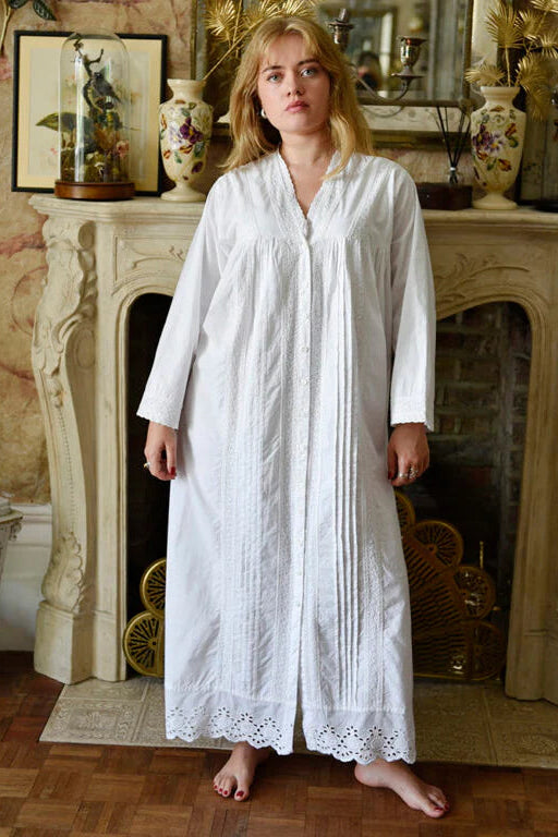 Woman in a long white dress standing in a room with decorative elements.