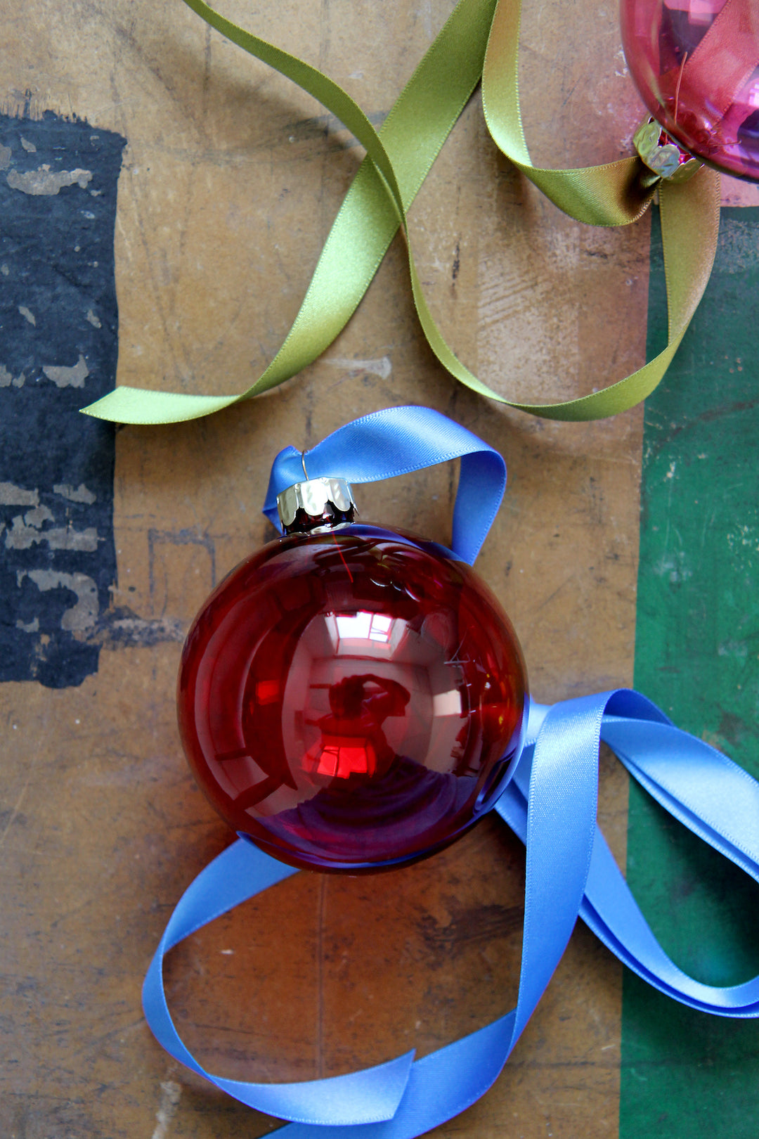 lifestyle image of clear red glass christmas bauble with blue ribbon on vintage chest from Domestic Science