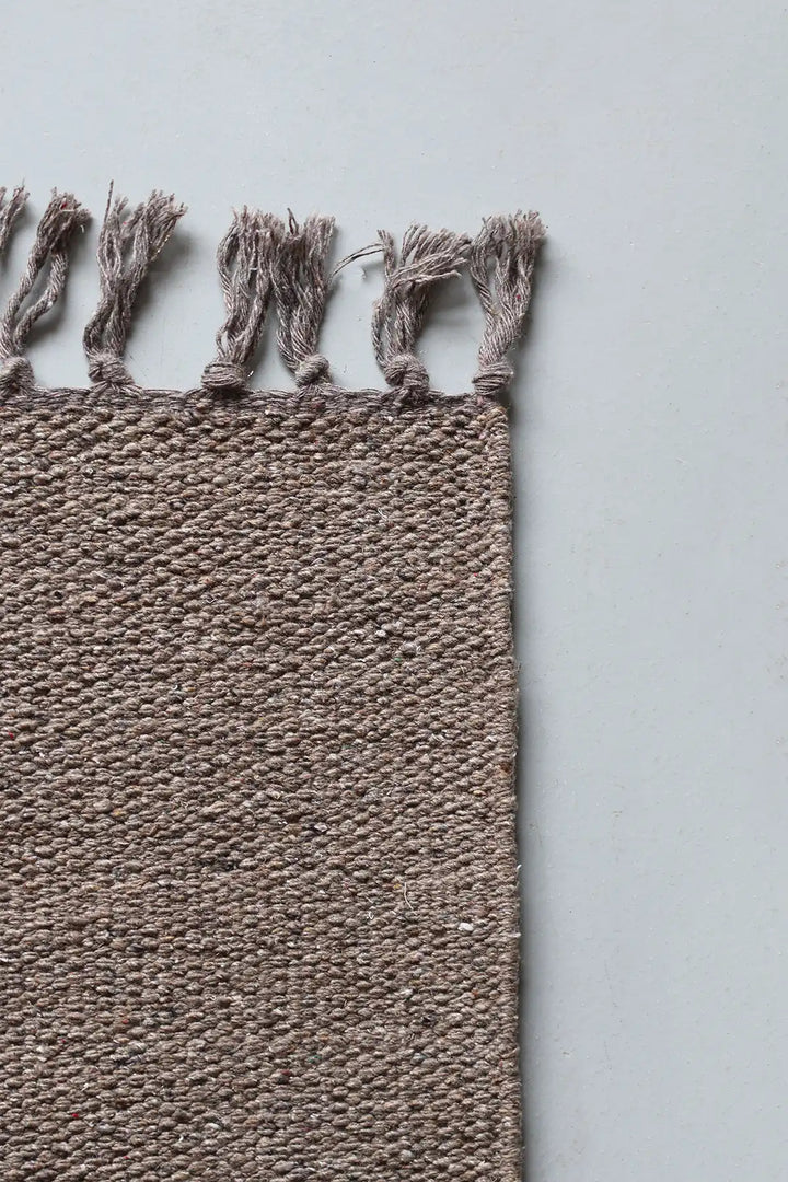 Textured brown rug with tassels on a light gray background