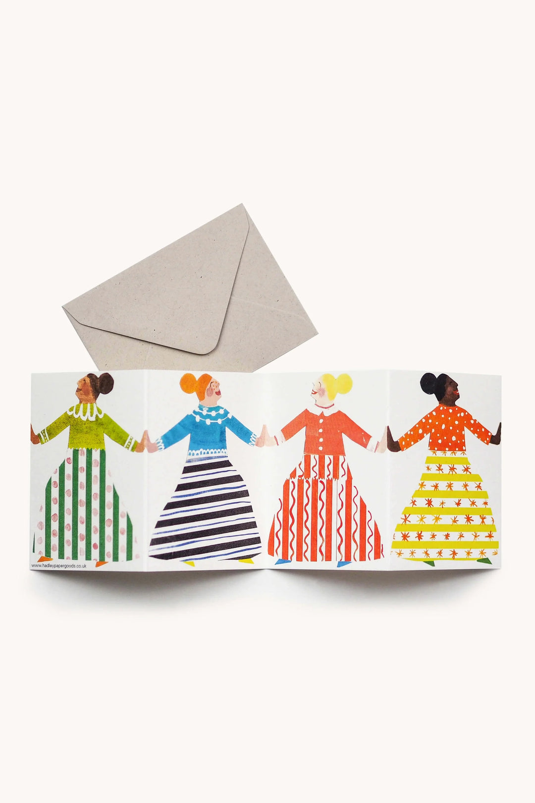 Greeting card with four illustrated women holding hands and a matching envelope on a white background