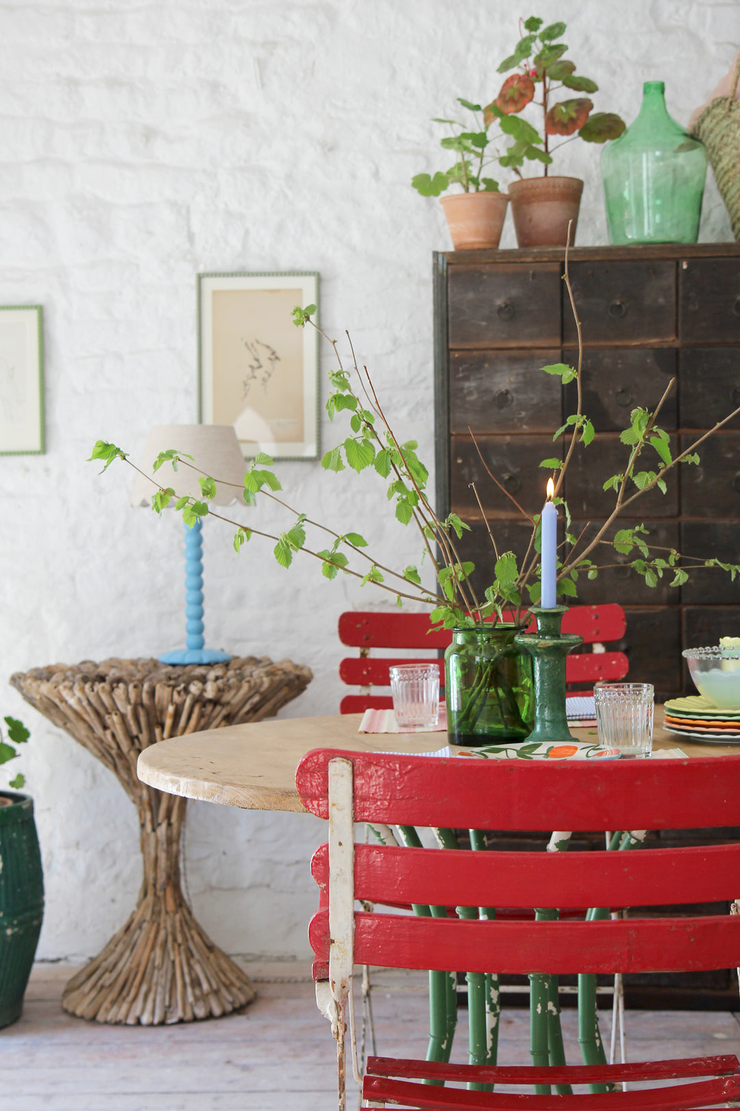 styled tablescape featuring a vintage faux bamboo table, red vintage garden chairs and scalloped colourful tableware portrait format