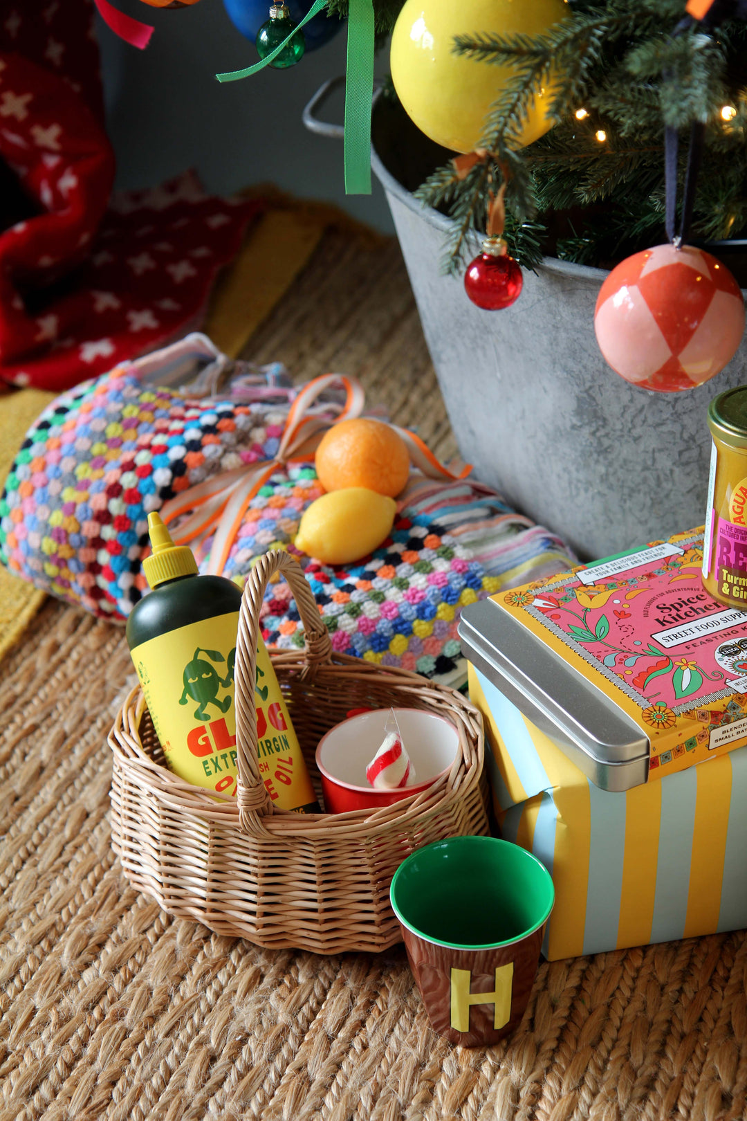 Decorative items including a basket with bottles, a potted plant with ornaments, and colorful boxes on a textured surface.