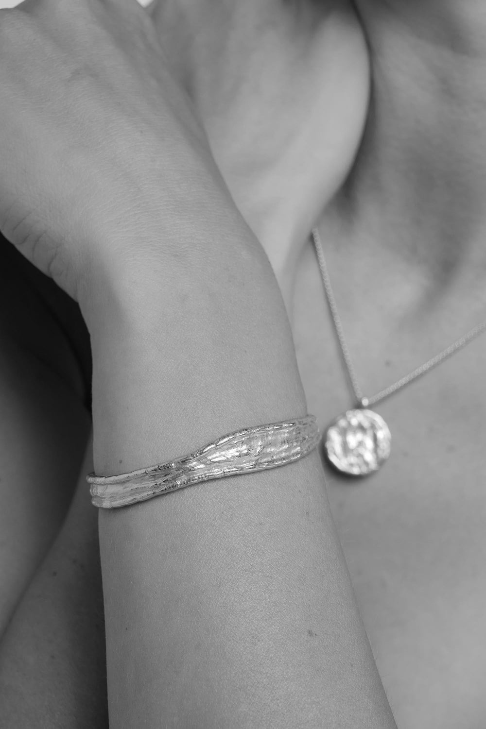 Close-up of a person wearing a silver driftline bangle and necklace.