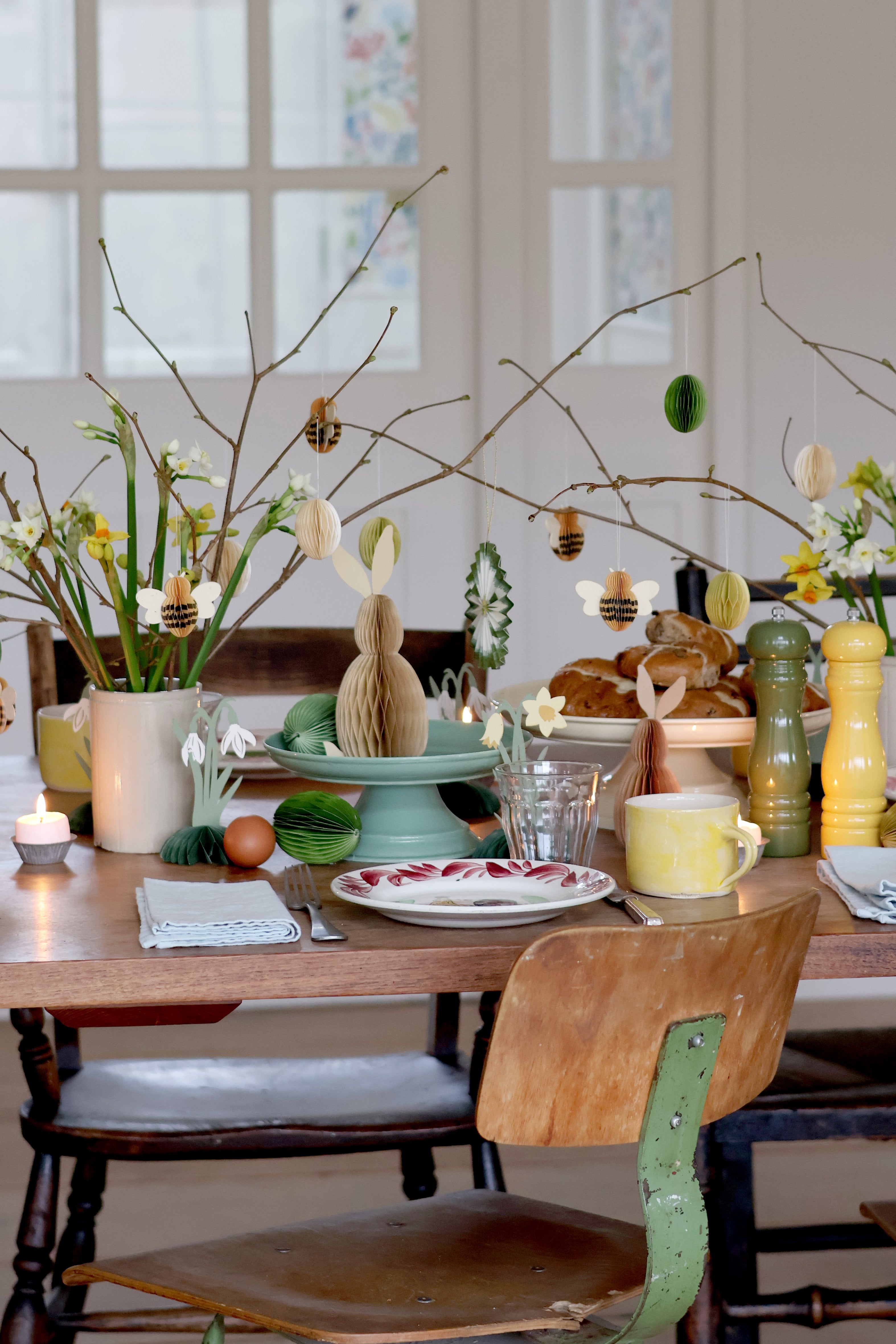 Dining table set with Easter decorations including eggs, flowers, and branches.