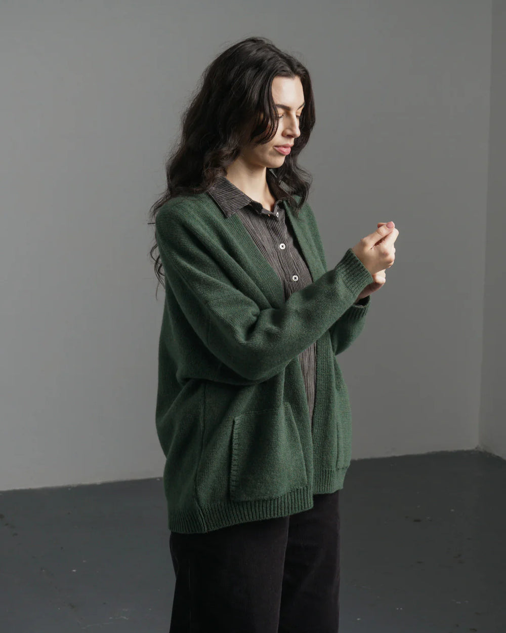 Person wearing a green sweater over a collared shirt against a gray background