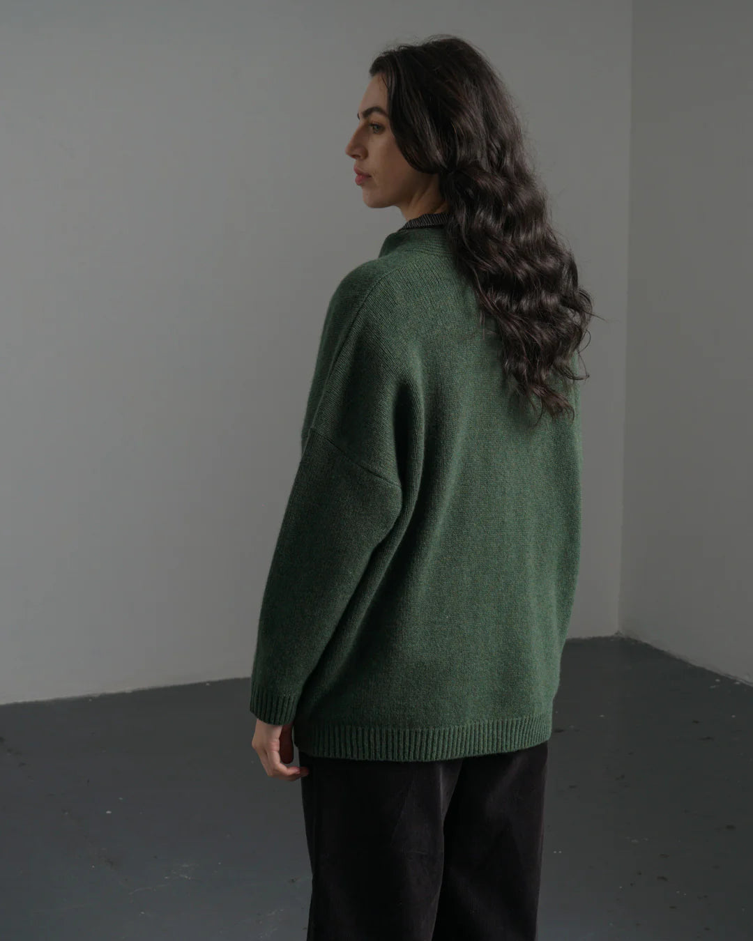 Woman wearing a green sweater against a plain background