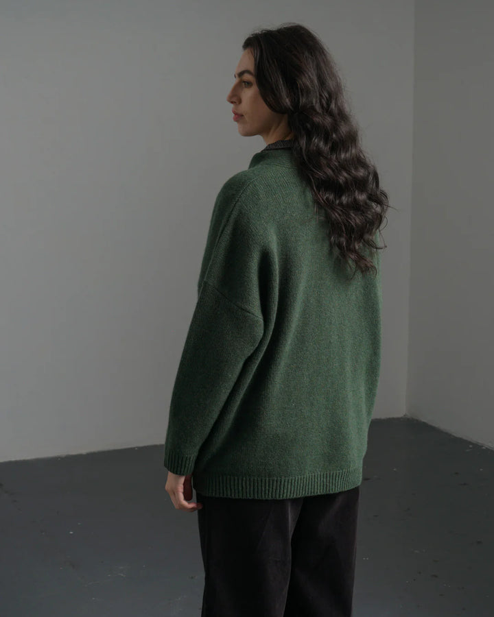 Woman wearing a green sweater against a plain background