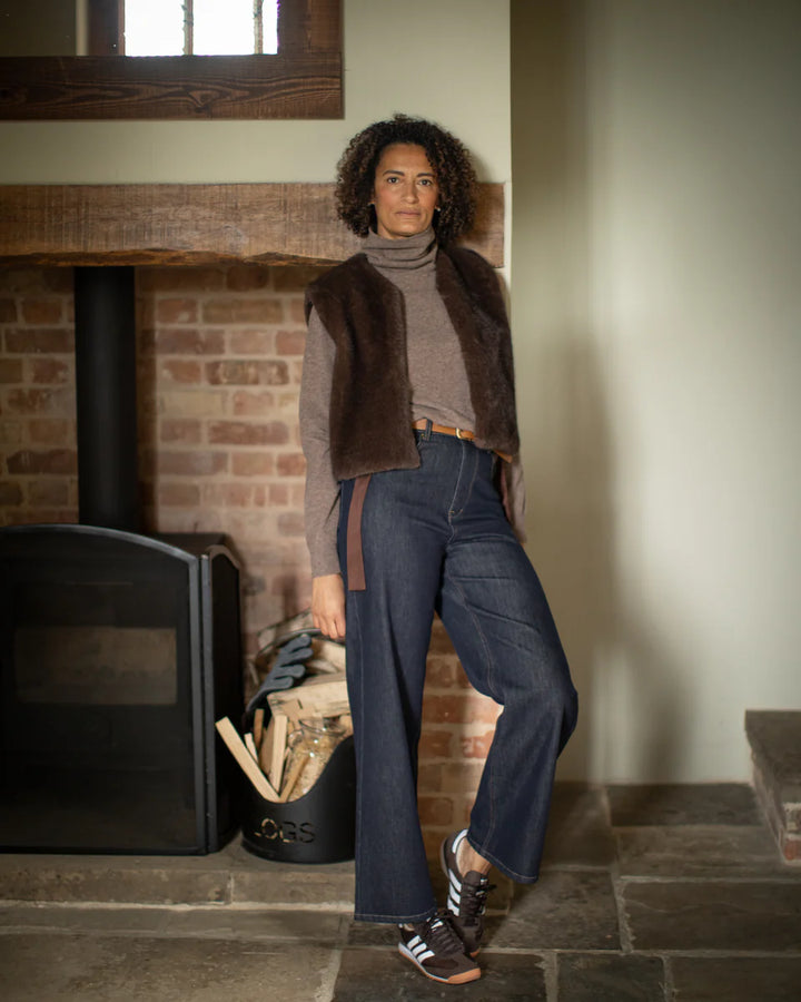 Woman standing in a room with a brick wall and wooden fireplace.