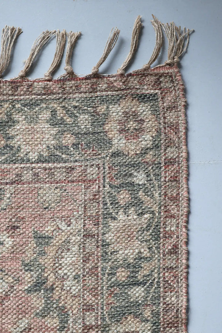 Close-up of a textured rug with tassels on a plain background