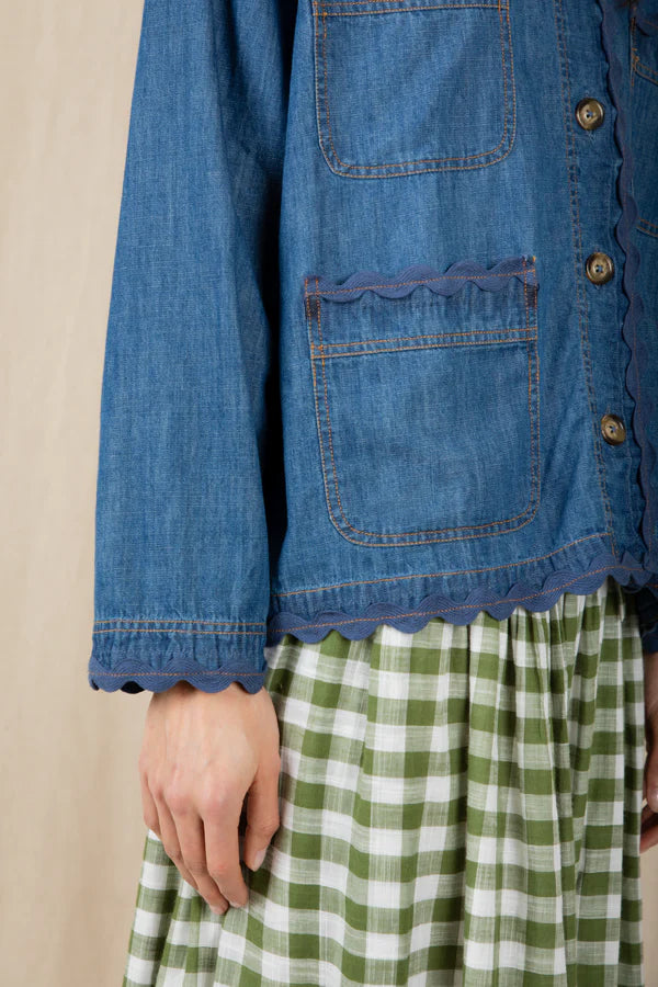 Blue denim jacket with a green and white checkered skirt on a beige background