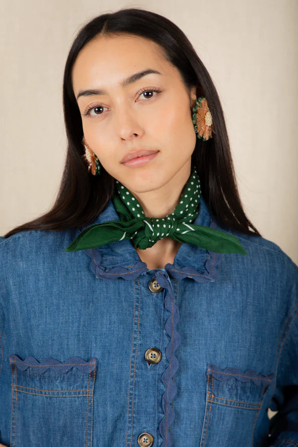 Woman wearing a green patterned scarf around her neck against a beige background