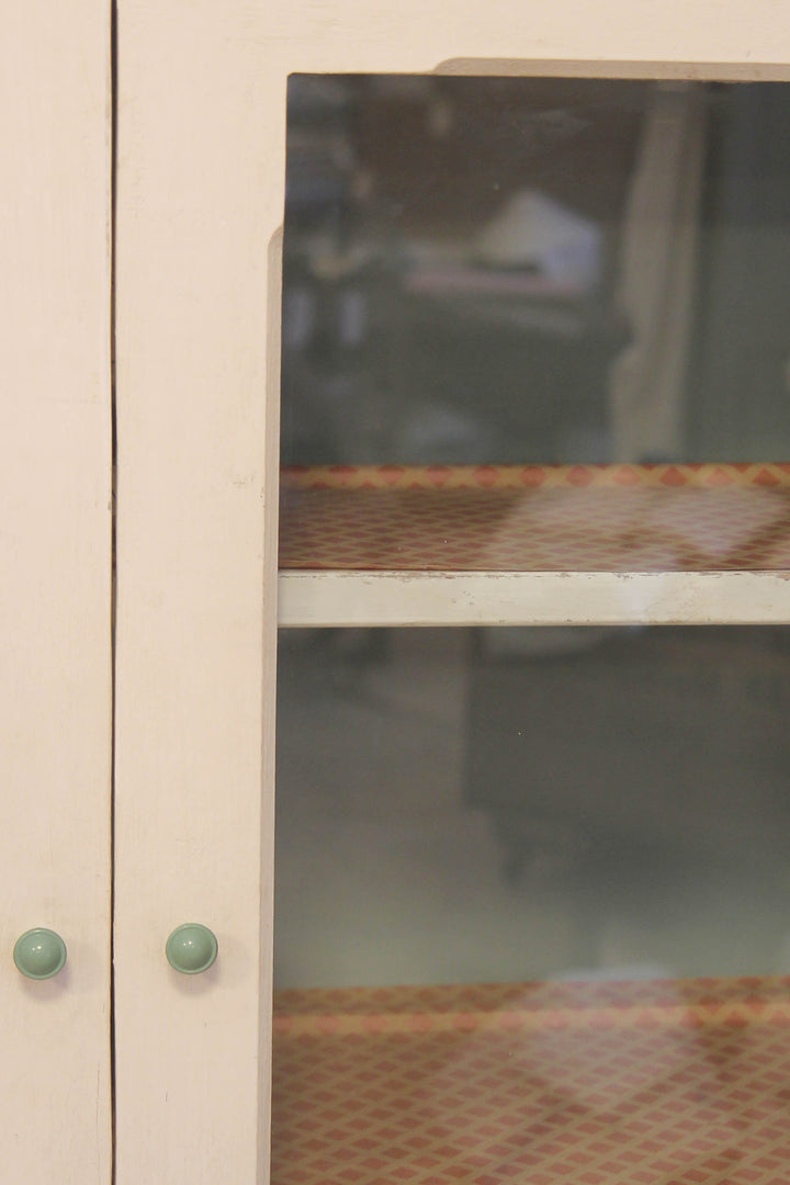 Close-up of a glass cabinet door with a wooden strip and green knobs.