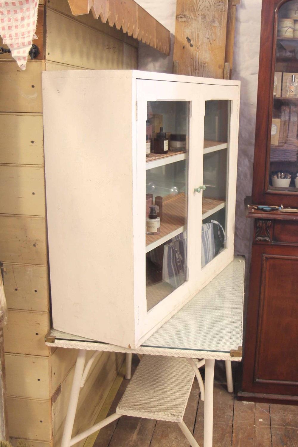 Vintage-style white cabinet with glass doors in a rustic interior setting.