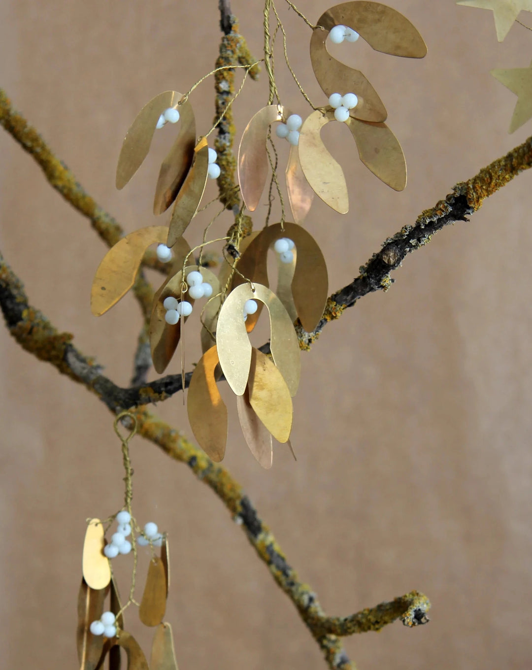 brass mistletoe hanging decoration with white beads hanging on a branch